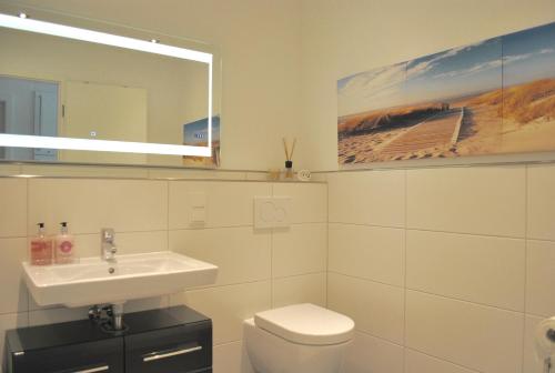 La salle de bains est pourvue d'un lavabo, de toilettes et d'un miroir. dans l'établissement The White Pearl inkl Wäsche Set, à Heiligenhafen