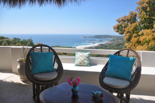two chairs and a table on a balcony with the ocean at Casa Cometa in San Agustinillo