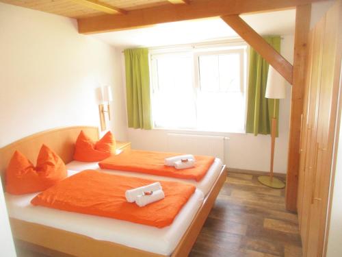 1 dormitorio con 2 camas con sábanas de color naranja y ventana en Casa Emmi, en Bad Mitterndorf