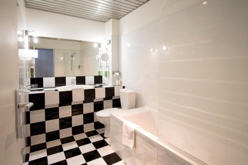 La salle de bains est pourvue d'un sol en damier noir et blanc. dans l'établissement Hôtel Raymond 4 Toulouse, à Toulouse