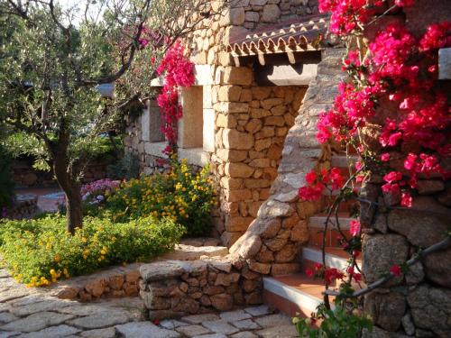 um edifício de pedra com flores ao lado em Residence L'Ea di Lavru - Appartamenti Mono-Bilo-Trilocali em Porto San Paolo