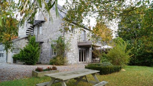 a wooden picnic table in front of a stone house at Gite Saboti in Dinant