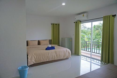 a bedroom with a bed with green curtains and a balcony at A.D. Living in Hua Hin