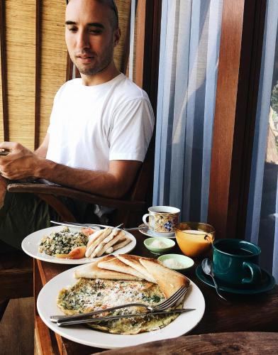 Een man aan een tafel met twee borden eten. bij Batan Sabo & Co in Nusa Penida