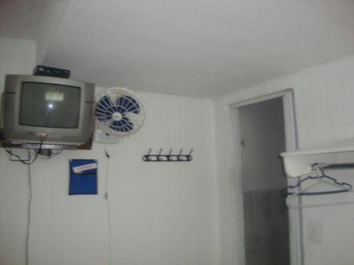 a room with a tv and a fan on the wall at Pousada III Poderes in Trindade