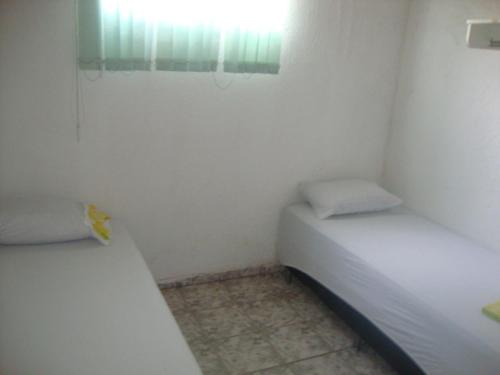 a small room with two beds and a window at Pousada III Poderes in Trindade
