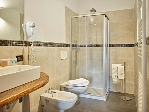 e bagno con doccia, servizi igienici e lavandino. di Romantic Hotel Excelsior a Cavalese
