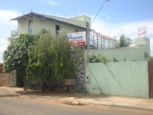 a building with a green fence and a tree at Pousada III Poderes in Trindade