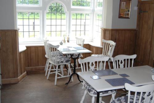 a dining room with tables and chairs and windows at Hare & Hounds Bed & Breakfast in Rye