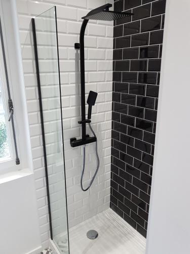 - une douche avec un mur carrelé noir et blanc dans l'établissement Nuit Zen Rouen - Jacuzzi - Centre Historique, à Rouen