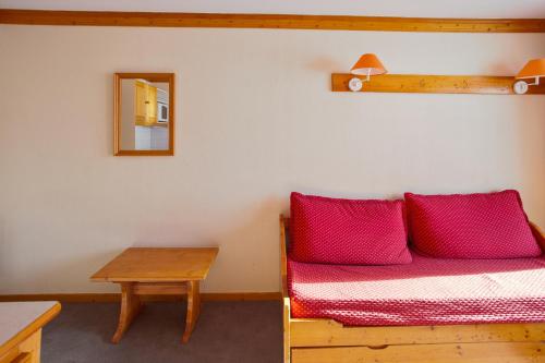 a room with a bed with red pillows and a table at Residence les Valmonts - maeva Home in le Chalmieux