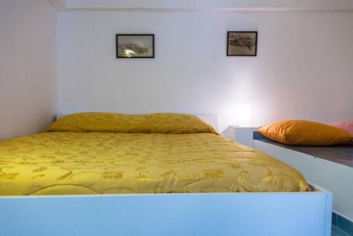a bedroom with a yellow bed with two pictures on the wall at B&B La Melodia in Anacapri