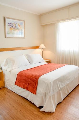 a bedroom with a large white bed and a window at Hotel Sunset Beach in Punta del Este