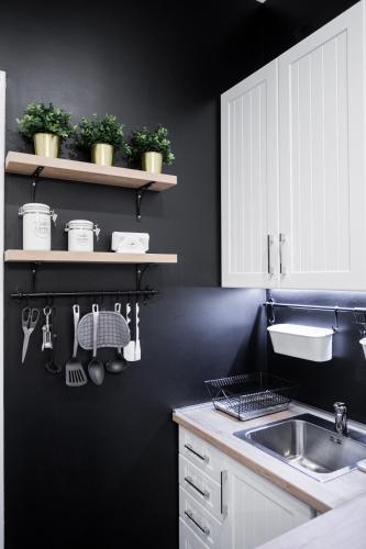 a kitchen with black walls and white cabinets and a sink at Apartment Eugen in Novi Sad