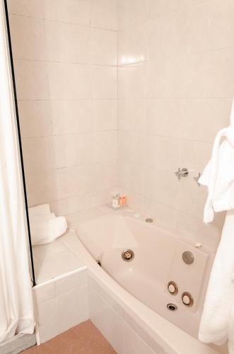 a white bathroom with a tub and a shower at Hotel Sunset Beach in Punta del Este