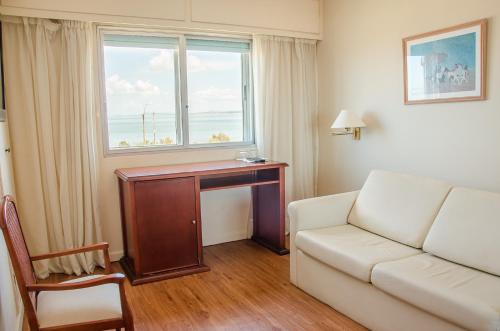 a living room with a couch and a table and a window at Hotel Sunset Beach in Punta del Este