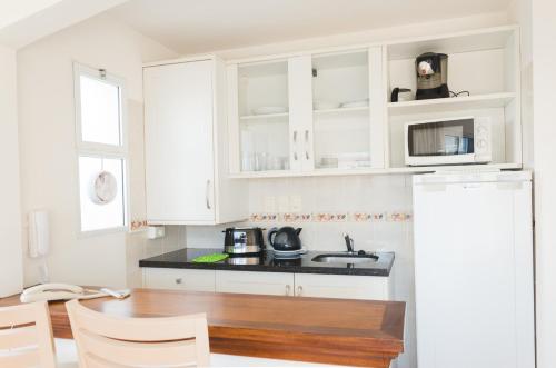 a kitchen with white cabinets and a wooden table at Hotel Sunset Beach in Punta del Este