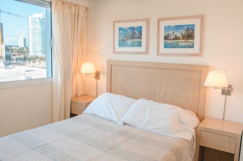 a bedroom with a bed with two lamps and a window at Hotel Sunset Beach in Punta del Este