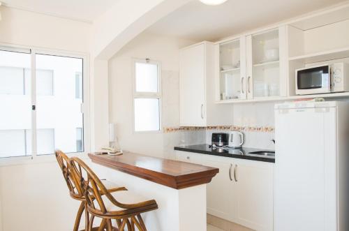 a kitchen with white cabinets and a wooden counter top at Hotel Sunset Beach in Punta del Este