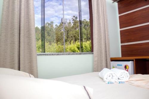 a bedroom with a bed and a window with towels at Pousada Monte Oliveira in Aparecida