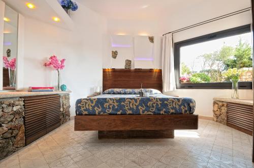 a bedroom with a large bed and a large window at Residence L'Ea di Lavru - Appartamenti Mono-Bilo-Trilocali in Porto San Paolo