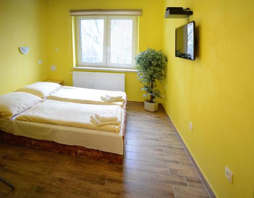 a yellow bedroom with a bed and a window at Penzion Čertovy Kameny in Jeseník