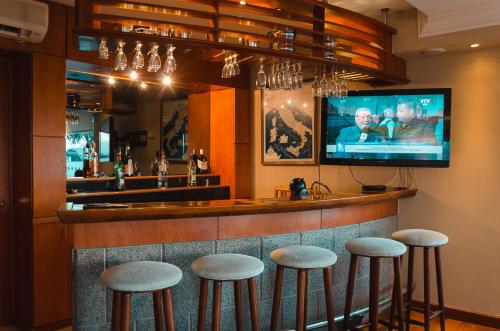 a bar with stools and a flat screen tv at Hotel Sunset Beach in Punta del Este