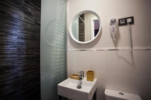 a bathroom with a mirror, sink, and toilet at CC Atocha in Madrid