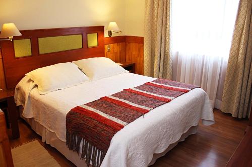 a bedroom with a large bed with a wooden headboard at Hotel Rucaitue in Osorno