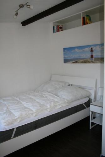 een wit bed in een kamer met een vuurtoren bij Haus am Priwallstrand in Travemünde
