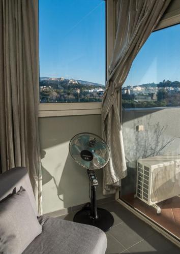 a bedroom with a fan in front of a window at Virgo - Loft with Spectacular View to Acropolis in Athens