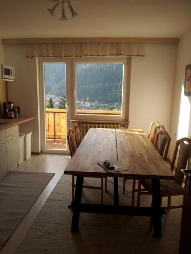 ein Esszimmer mit einem Holztisch und einem großen Fenster in der Unterkunft Haus Olympia in Pfunds