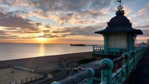 a view of a lighthouse and the beach at sunset at Old Palace Guest House in Brighton & Hove