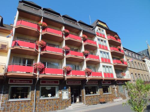 un edificio con balcones rojos y flores. en Hotel Moselkern en Moselkern