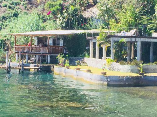 a house with a deck on the water at Lake Front Suite at Los Elementos in Santa Cruz La Laguna