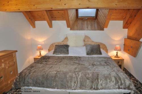 ヴァロワールにあるHôtel-Chalet les Mélèzesのベッドルーム1室(大型ベッド1台、ランプ2つ付)
