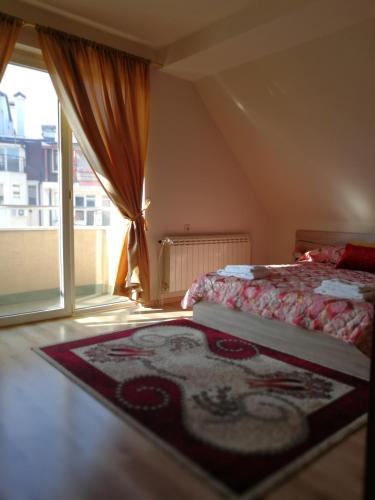 a bedroom with a bed and a large window at Full Rooms in Kyustendil