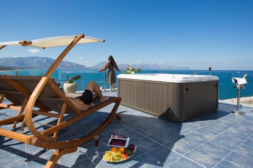 a woman sitting in a chair next to a hot tub at Marina Holiday & Spa in Balestrate