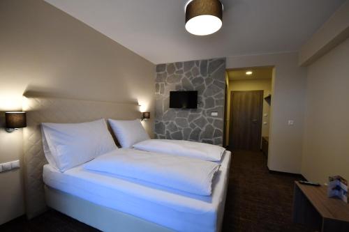 a bedroom with a bed with white sheets and a tv at Hotel Studničky in Vernár