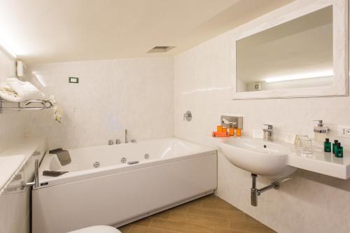 a white bathroom with a tub and a sink at Marina Holiday & Spa in Balestrate