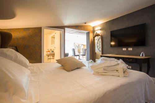 a bedroom with a white bed with a television on the wall at Marina Holiday & Spa in Balestrate