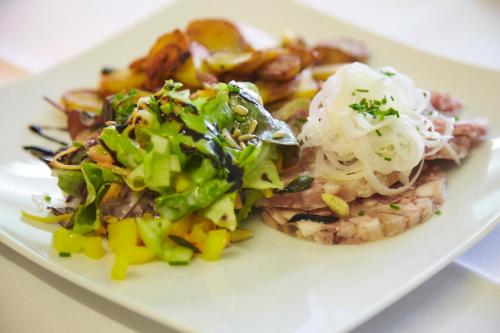 a white plate with a salad and other food on it at Flair Hotel Grüner Baum in Donaueschingen