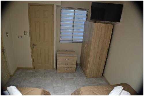 a bedroom with a bed and a dresser and a television at Hotel Herencia in Chillán