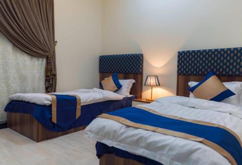 um quarto com 2 camas em azul e branco em منازل الورد للشقق المخدومه Tabuk Risdance em Tabuk