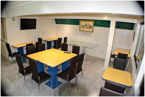 a dining room with tables and chairs and a flat screen tv at Hotel Herencia in Chillán