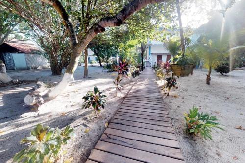 a wooden pathway in the middle of a beach with trees at Condo #31 @ Beachside Villas in Placencia Village
