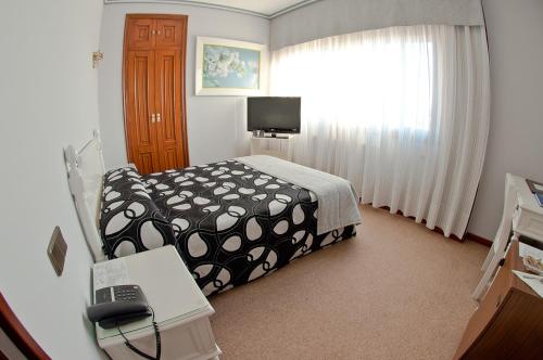 a hotel room with a bed and a television at Hotel Don Pepe in Poio