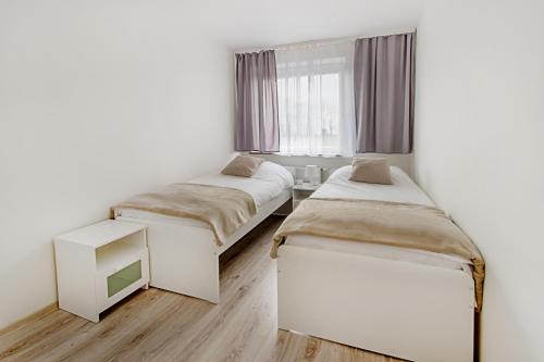 a bedroom with two beds and a tv in it at Apartament Poniatowskiego - Komfortowe Noclegi in Piaseczno