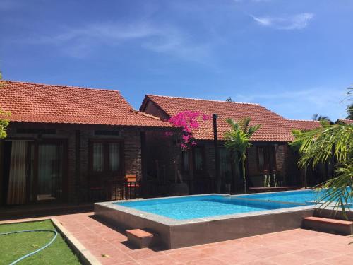 a swimming pool in front of a house at MAY Bungalow in Mui Ne