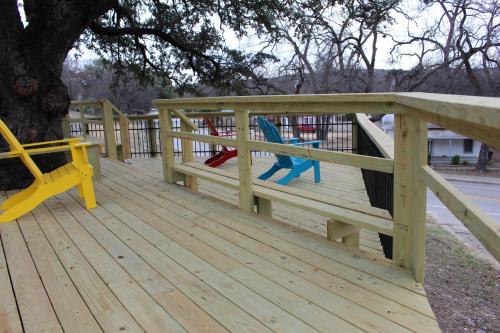 a wooden deck with two chairs and a tree at Live Oak B&B in Glen Rose
